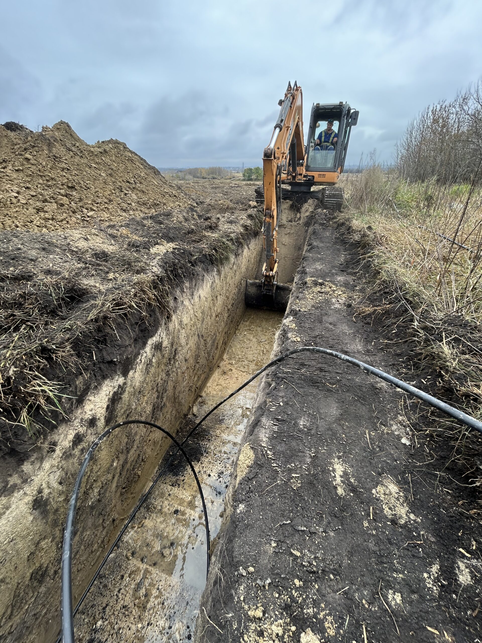 Geothermal ground loop trenching and pipe installation in Manitoba